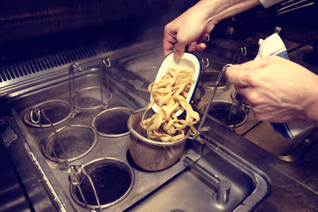 Chef is cooking pasta at commercial kitchen, toned imageの写真素材