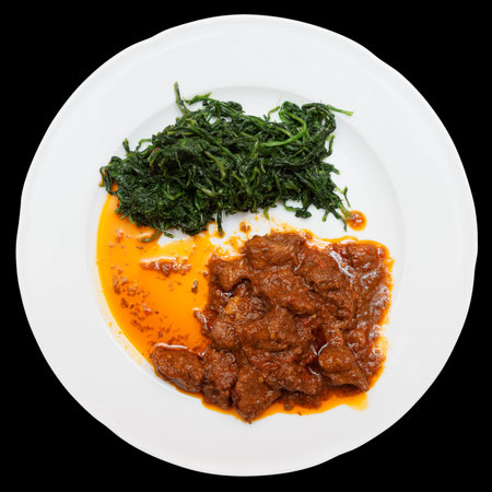 Wild boar stew with hot sauce and spinach isolated on black