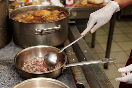 Chef is frying lamb slices in oil, commercial kitchenの写真素材