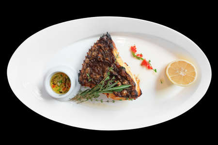 Grilled flounder on plate, isolated on black backgroundの写真素材