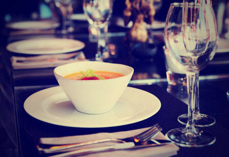 Dish with pumpkin soup on set restaurant table, toned imageの写真素材
