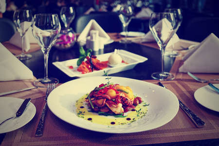 Seafood appetizer and tasty dessert on restaurant table, toned imageの写真素材