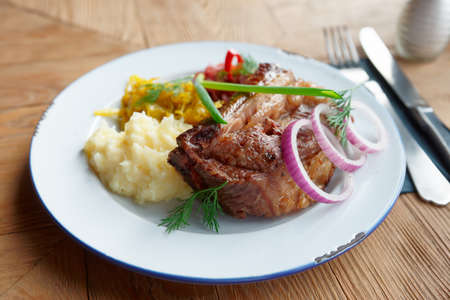 Fried pork ribs with sauerkraut and mashed potatoes on restaurant tableの写真素材