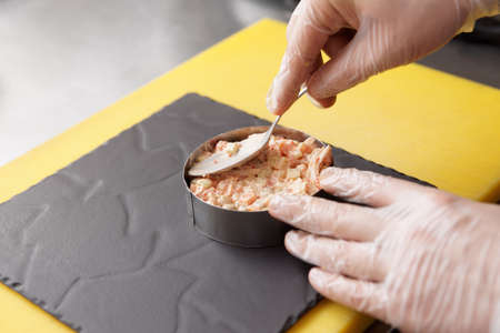 Chef is serving appetizer on slate plate with metal ring, commercial kitchenの写真素材