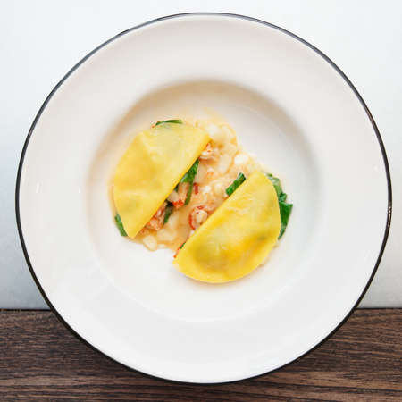 Ravioli-like dish with crayfish, apples and herbs shot from above on restaurant tableの写真素材