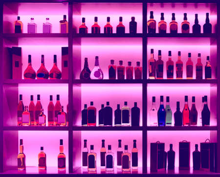 Various alcohol bottles in a bar, back light, all logos removed, toned imageの写真素材