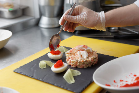 Chef is decorating crab salad with flying fish roe in restaurant kitchen