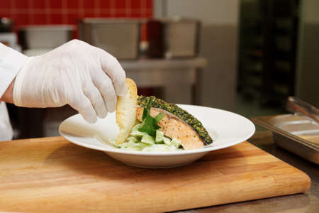 Chef is decorating a fish dish with grilled bread sliceの写真素材