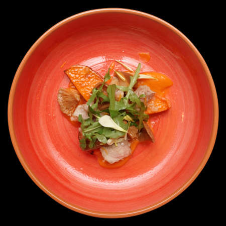 Game bird fillet with sweet potato mash and mushrooms in red clay plate, isolated on black backgroundの写真素材