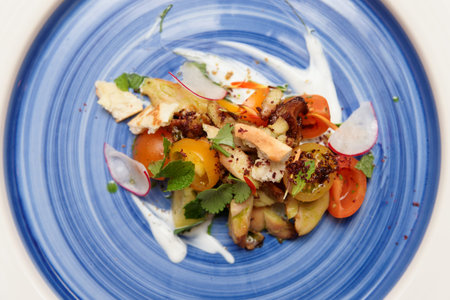 Chicken salad with vegetables on blue plate shot from above