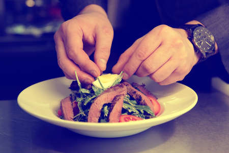 Professional chef is making appetizer with meat in commercial kitchen, toned imageの写真素材