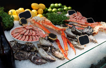 Raw crab legs, shrimps and oysters on ice in seafood restaurantの写真素材