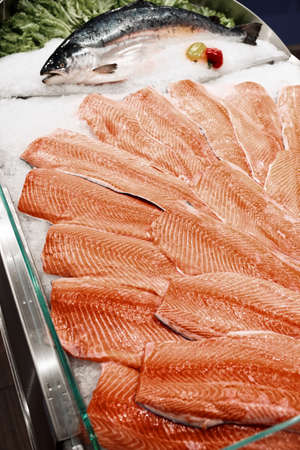 Salmon fillets and whole fish on cooled market display, toned imageの写真素材