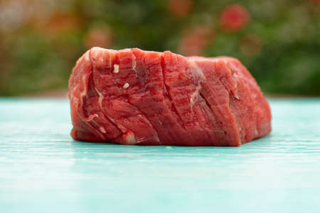 Raw tenderloin steak on blue board shot outdoors in rose gardenの写真素材