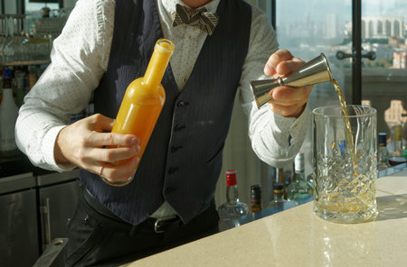 Mixologist is pouring alcohol ingredients into mixing glass