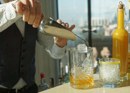 Barman is adding ice to mixing glass, making cocktailの写真素材