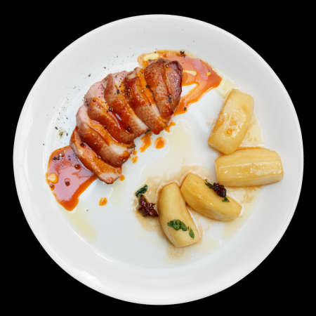 Duck fillet with apples and orange sauce isolated on blackの写真素材