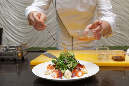 Chef is sprinkling salad dressing on salmon roll appetizerの写真素材