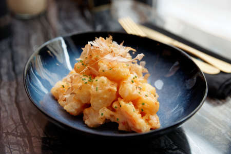 Shrimps cooked in Asian style in batter with sweet-sour sauce and bonito tuna on marble tableの写真素材
