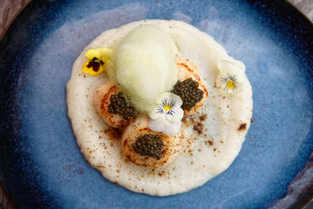 Grilled scallops with caviar and molecular froth on blue clay plateの写真素材