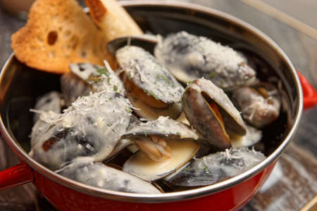 Mussels cooked with creamy sauce and served in metal casserole, close-upの写真素材