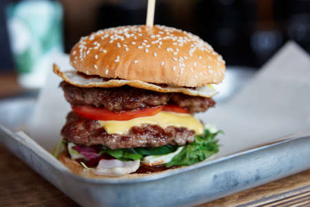 Big burger on restaurant table, close-up, focus on the bunの写真素材