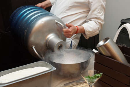 Chef is pouring liquid nitrogen from a large Dewar flaskの写真素材