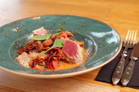 Grilled tuna with salami and girole mushrooms on restaurant tableの写真素材