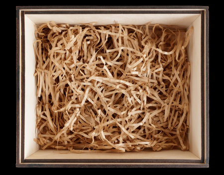 Wooden box with shredded paper, shot from above, isolated on black background