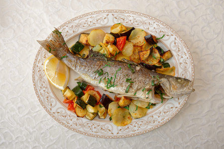 Fried sea bass with baked vegetables shot from above, Italian dish