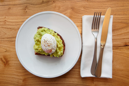 Grilled bread with guacamole and poached egg shot from above on wooden table