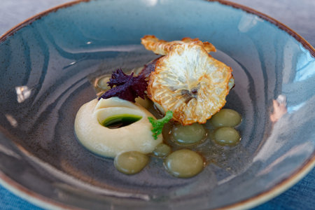 Creative appetizer of hummus, fried celeriac, green aromatic oil and fruit gel in clay plate,...