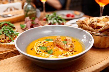 Deep plate with pumpkin soup and another food, Italian dinner in a restaurant