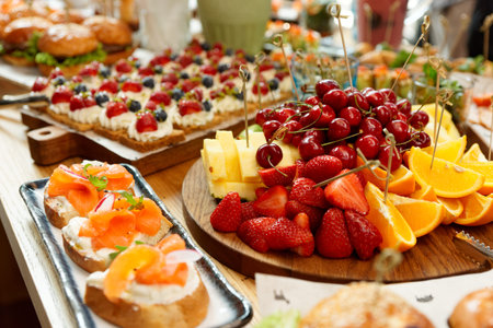 Fruits, berries, fish snacks and dessert on catering restaurant tableの写真素材