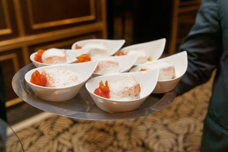 Waiter carries tray with banquet food plates - salmon and foamy sauce