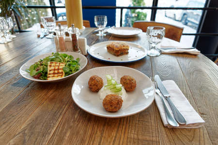 Set of three Greek dishes - fried Saganaki cheese, moussaka and zucchini fritters on restaurant tableの写真素材