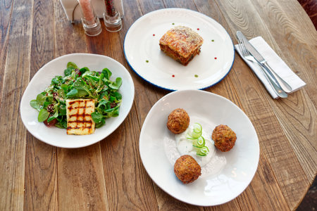Set of three Greek dishes - fried Saganaki cheese, moussaka and zucchini fritters on restaurant...