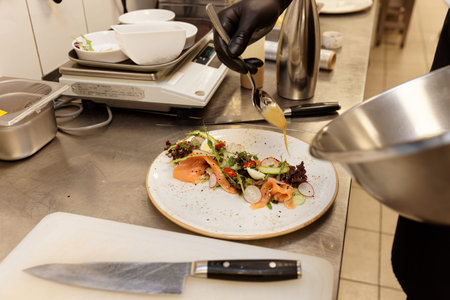Chef is cooking salmon salad in commercial kitchen