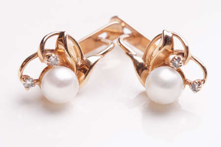 Pair of earrings with pearls shot on light reflective surfaceの写真素材
