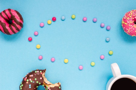 Sweet donuts with coffee and colorful candies on the blue background. Delicious donut.の写真素材