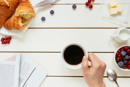 Tasty breakfast with coffee, berries, croissant on the white wooden table with copy space, top viewの写真素材