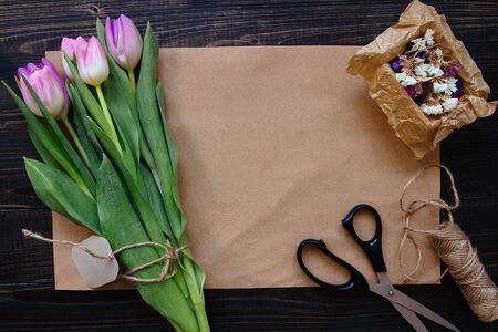 Bouquet of beautiful fresh tulips with accessories on the wooden background. Florist workplace.の写真素材