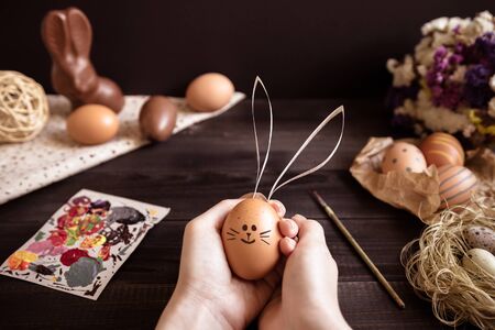 Easter bunny. Female hands holding easter egg on the wooden table.の写真素材
