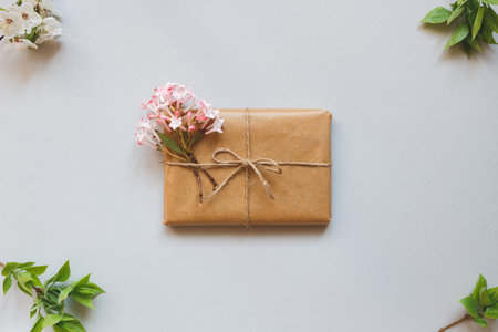 Cute gift box wrapped with craft paper and flowers top view. Gift for any spring holiday.の写真素材
