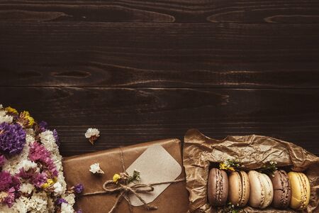 Delicious chocolate macaroons and gift on the wooden table, with copy space. Top view.の写真素材