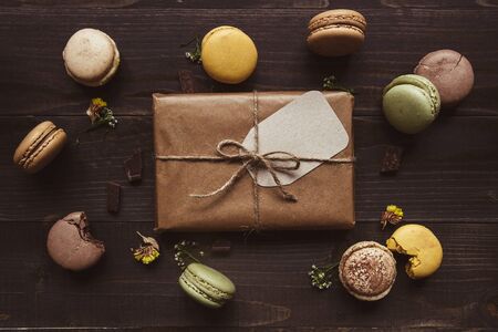 Delicious chocolate macaroons and gift on the wooden table, top view.の写真素材