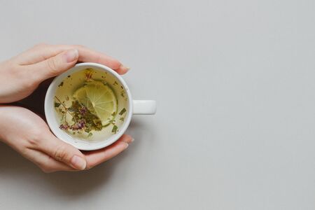 Tea background. Hands holding cup of hot green tea on the gray background, top view. Copy space.の写真素材