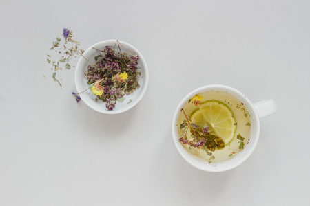 Tea time. Cup of hot herbal tea and dry tea on the gray background, top view.の写真素材