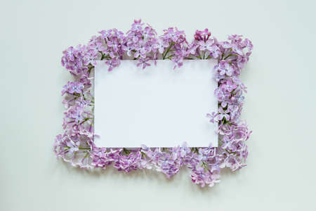 Flower background with paper sheet. Beautiful fresh flowers and leaves on gray background, with copy space.の写真素材