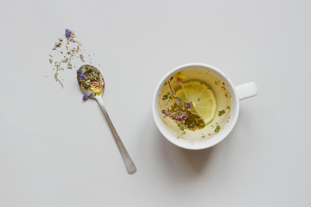 Tea time. Cup of hot herbal tea and dry tea on the gray background, top view.の写真素材